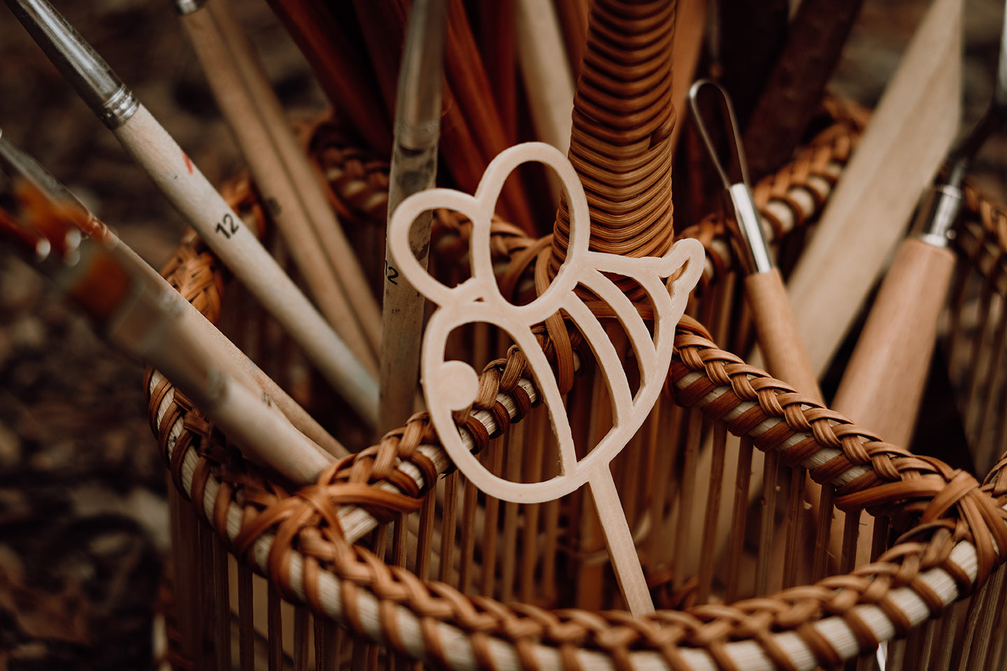 Kinfolk Pantry bee shaped eco bubble wand, placed in a stand with paintbrushes outside in nature.