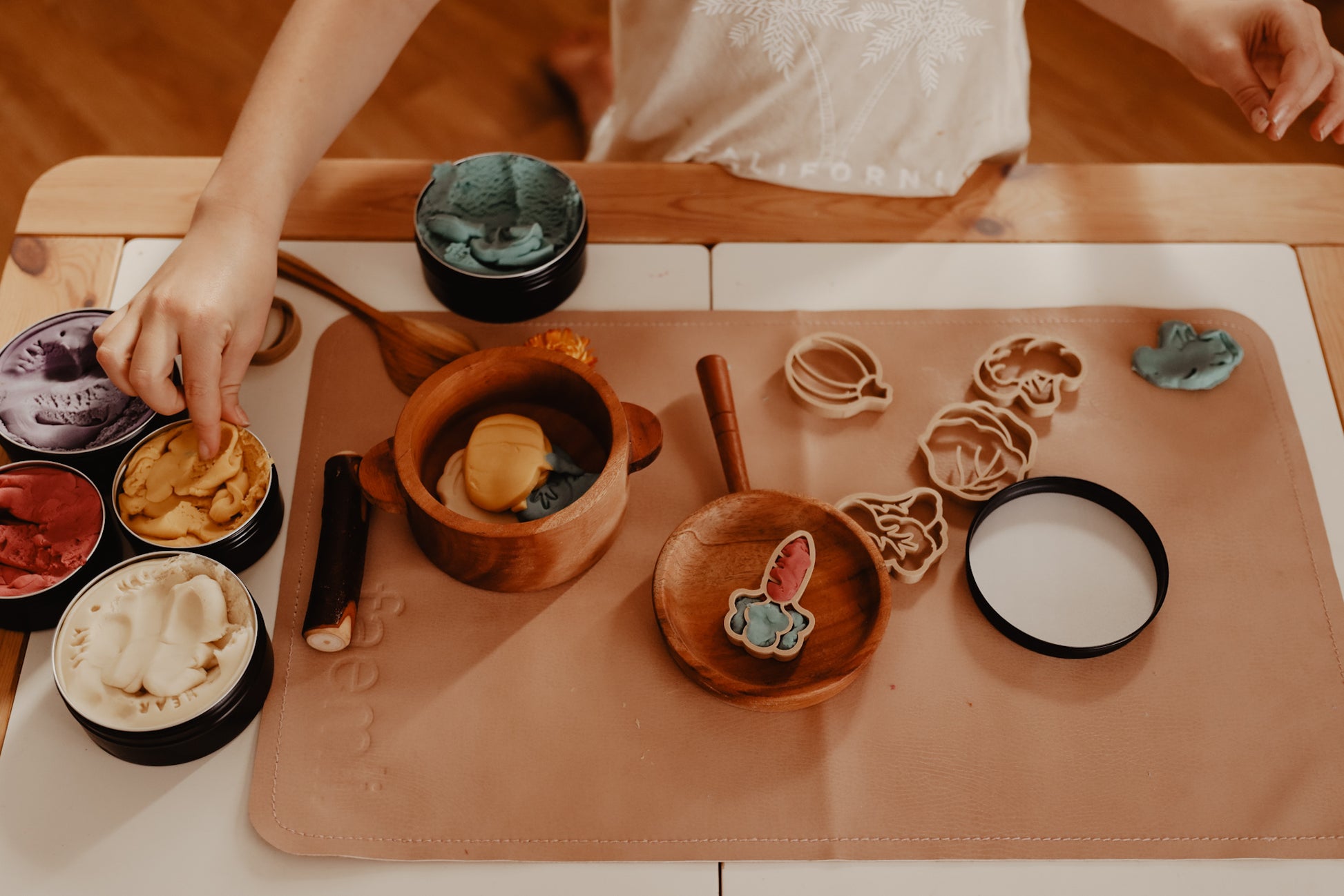 Kinfolk Pantry eco vegetable shaped playdough cutters. A toddler is using different coloured playdough to create the vegetable shapes and has then set up a pretend kitchen using the vegetable playdough shapes created to add to the pots and pans.
