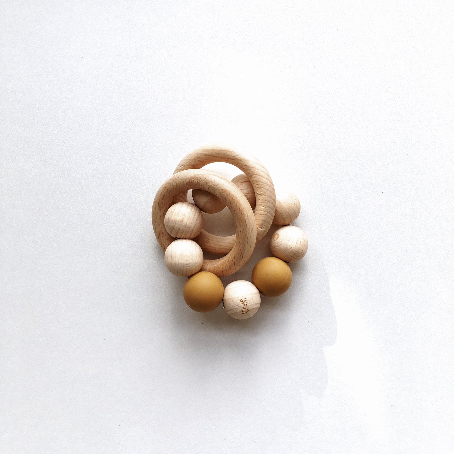 Bezisa wooden baby rattle with a mix of round wooden beads and camel coloured 100% silicone beads, plus two wooden rings. Product is photographed on a plain white background.