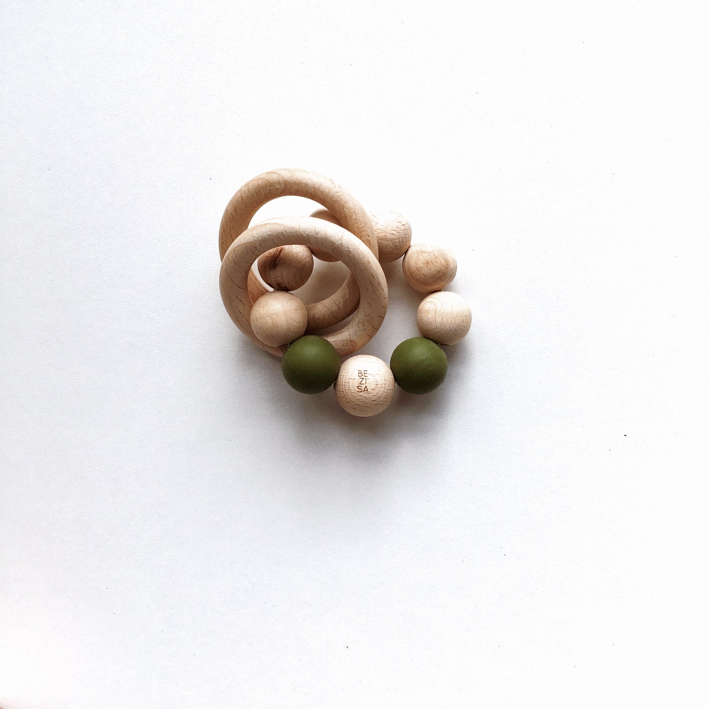 Bezisa wooden baby rattle with a mix of round wooden beads and olive coloured 100% silicone beads, plus two wooden rings. Product is photographed on a plain white background.