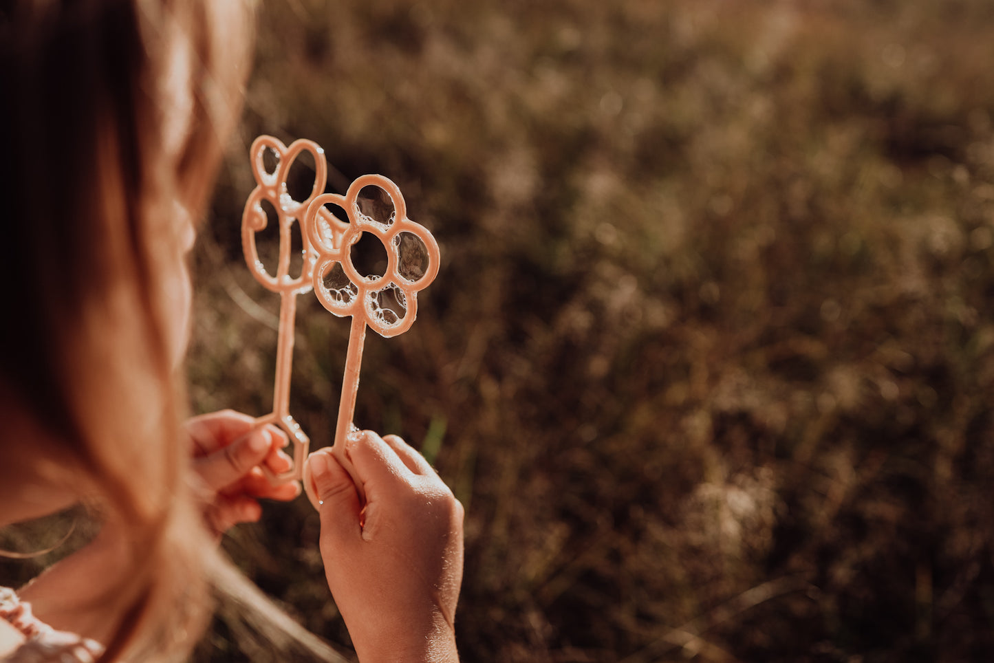A little girl is holding the bee and flower Kinfolk Pantry eco bubble wands.