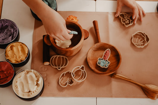 Kinfolk Pantry eco vegetable shaped playdough cutters. A toddler is using different coloured playdough to create the vegetable shapes and has then set up a pretend kitchen using the vegetable playdough shapes created to add to the pots and pans. 
