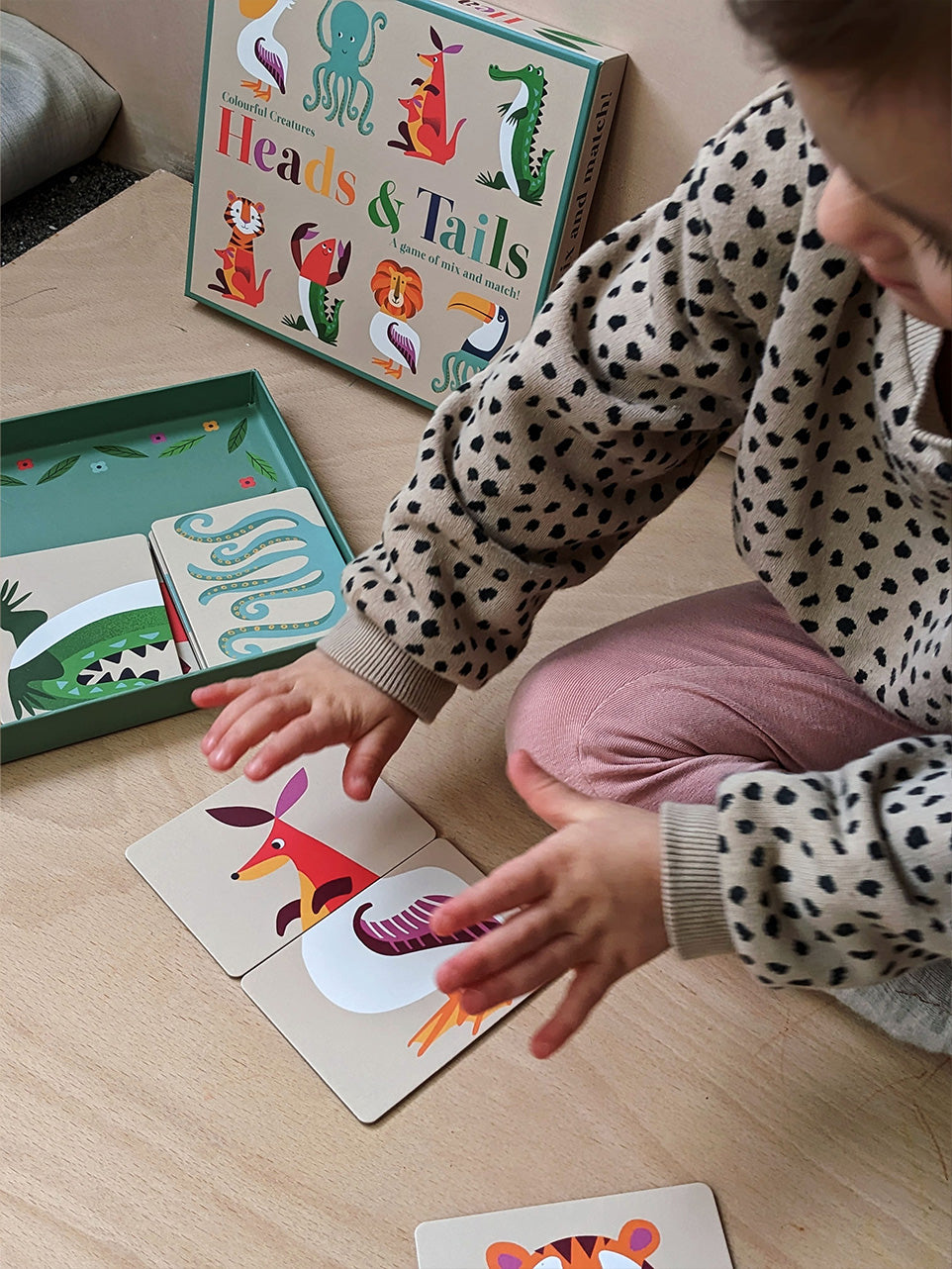 Toddler creating silly animals as she tries to match up the heads and tails of the animals in this card game